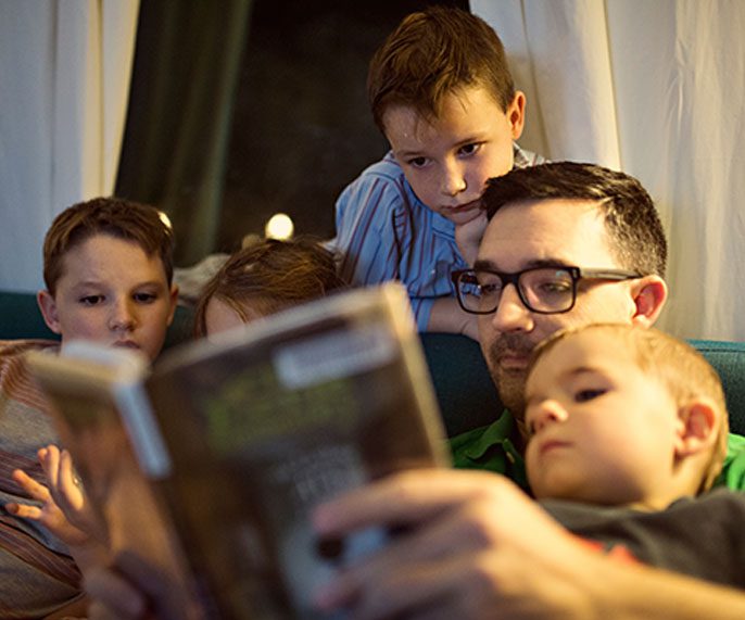 Dad reading books to his young children